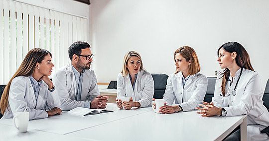 Gruppe von Ärztinnen und Ärzten diskutiert am Tisch