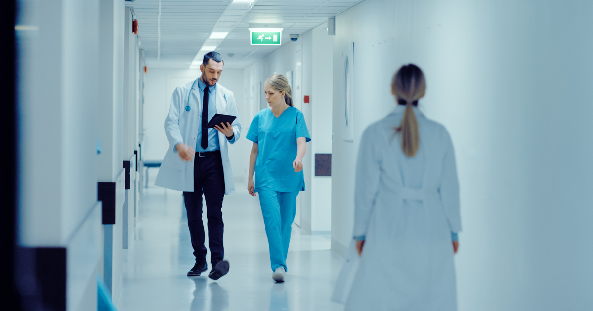 Junge Chirurgin und Arzt mit Tablet im Krankenhausflur